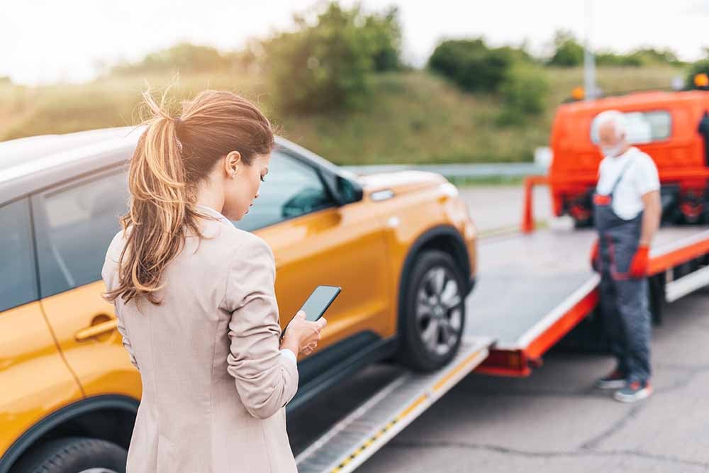 Femme qui contacte son assureur pendant que son véhicule se fait remorquer