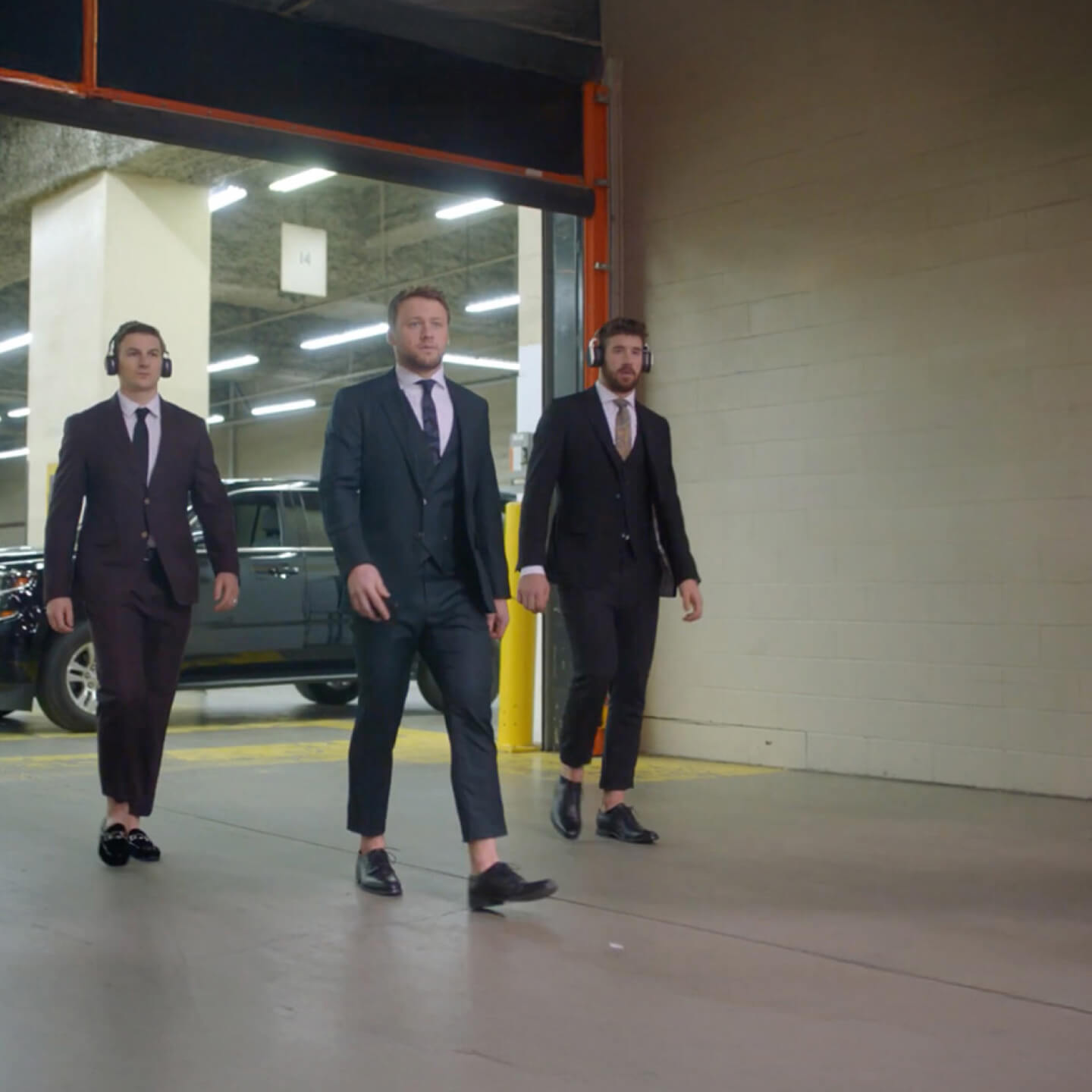Zach Hyman, Morgan Rielly and Frédérik Gauthier dressed in suits walk from an SUV down a hallway before a hockey game. The Sonnet home and auto logo is on the wall.
