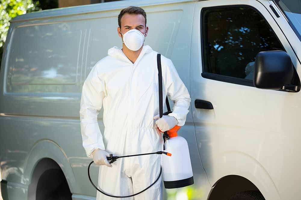 Technicien en lutte antiparasitaire debout devant une fourgonnette blanche