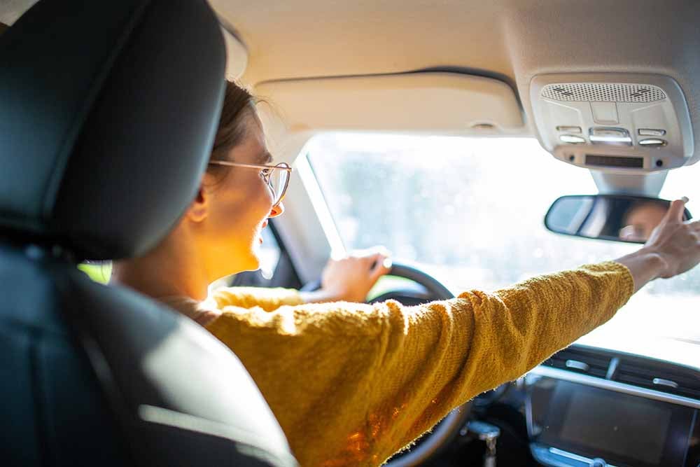 Une jeune femme ajuste le rétroviseur de sa voiture