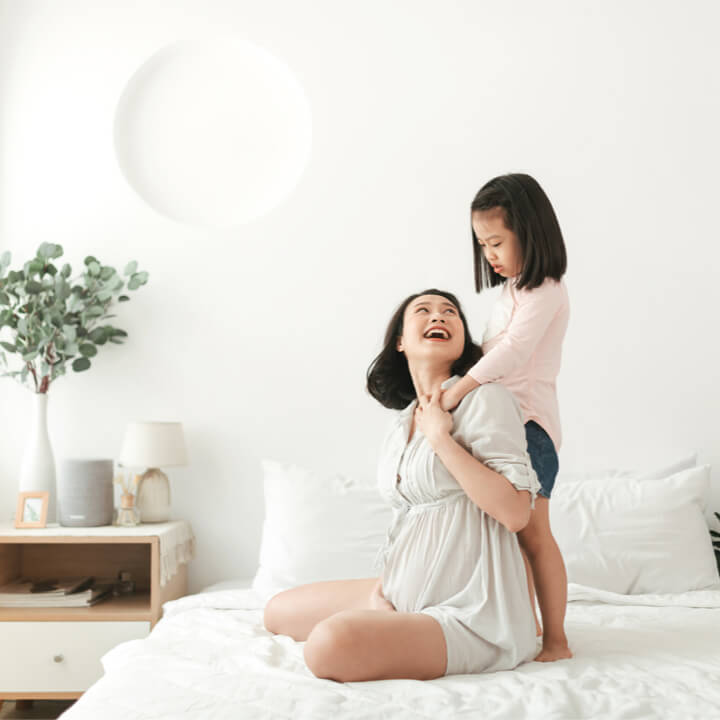 Mother and daughter laughing on bed