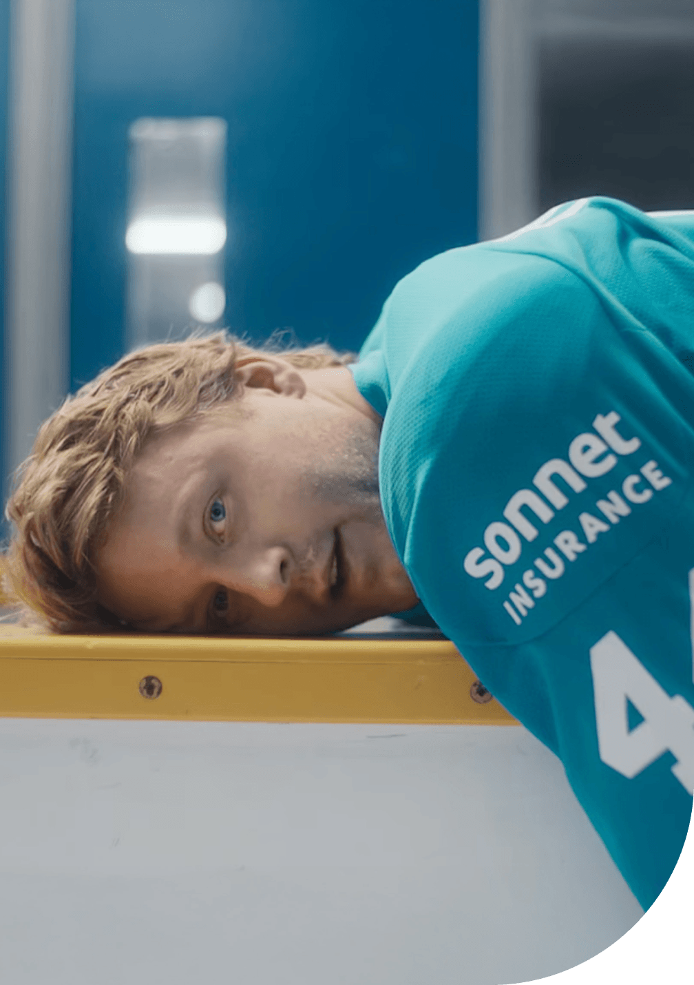 Morgan Rielly of the Toronto Maple Leafs wearing a teal Sonnet Insurance jersey with number 44, lying on the boards inside a hockey arena.