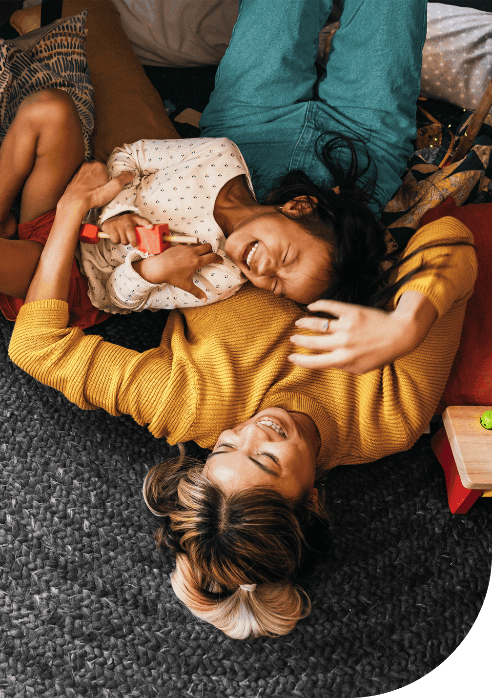 Une mère et son enfant allongés sur un tapis, riant et jouant ensemble à la maison.