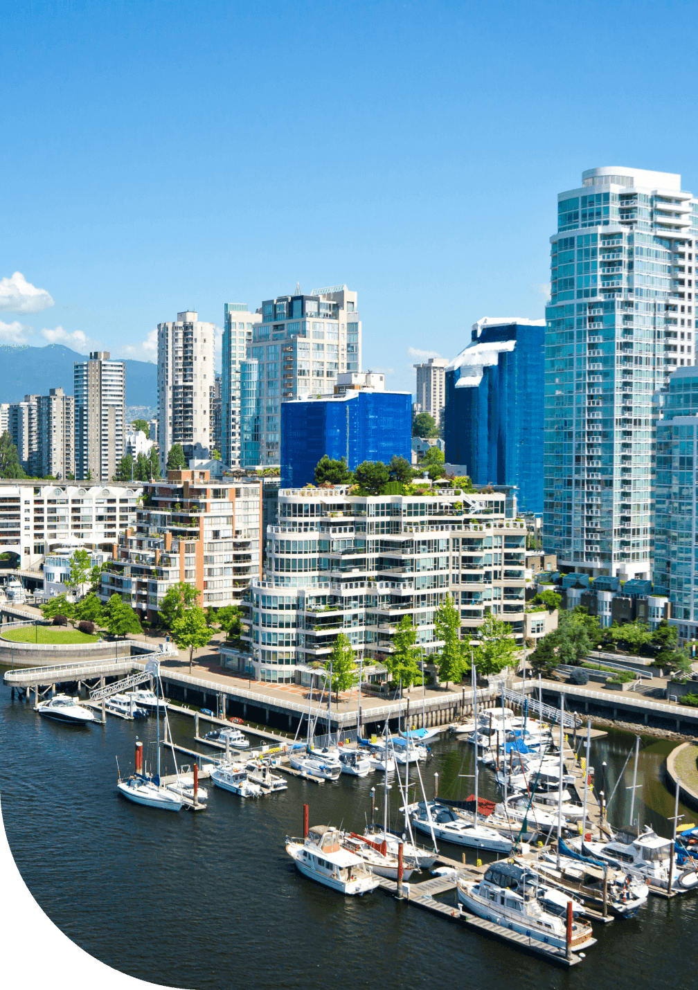 A city scene of BC condos overlooking the ocean with mountains in the background.