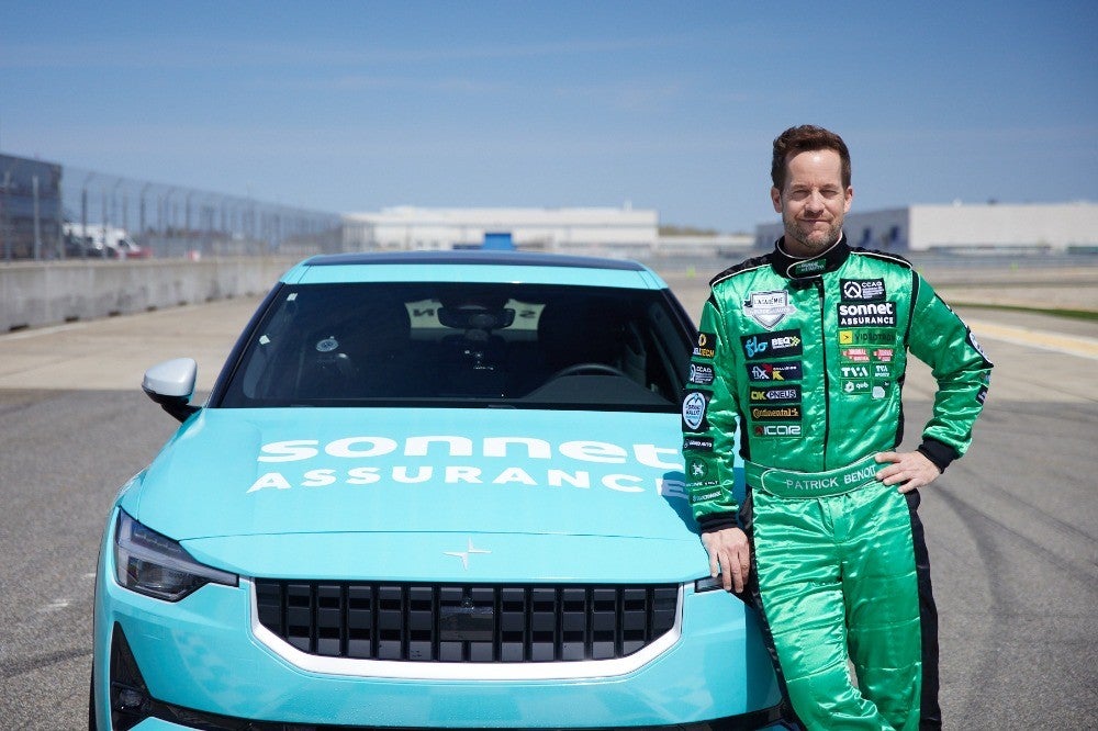 Patrick Benoit devant la voiture officielle de l'Académie du Guide de l'auto aux couleurs de Sonnet Assurance.