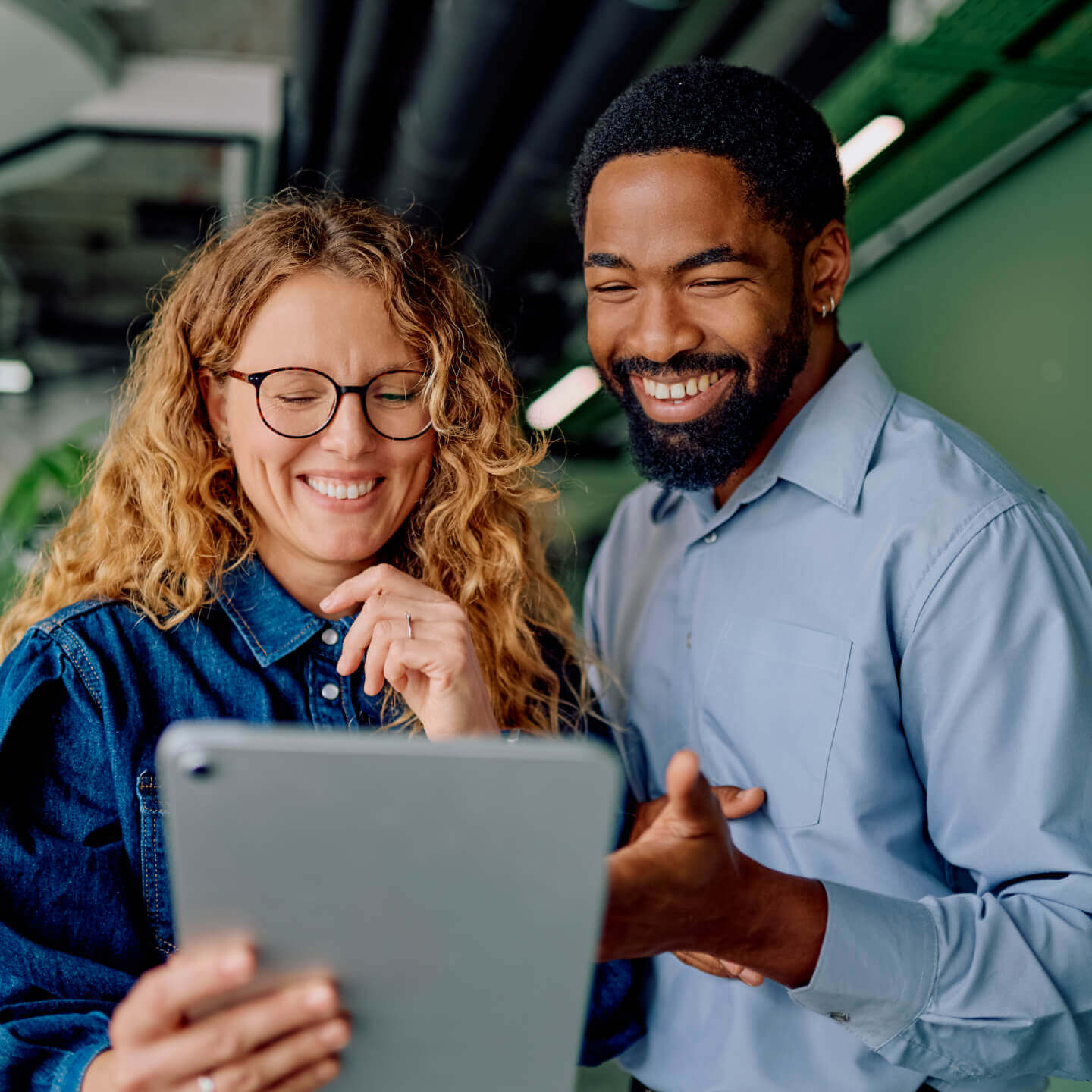 Two coworkers reviewing work on a tablet.
