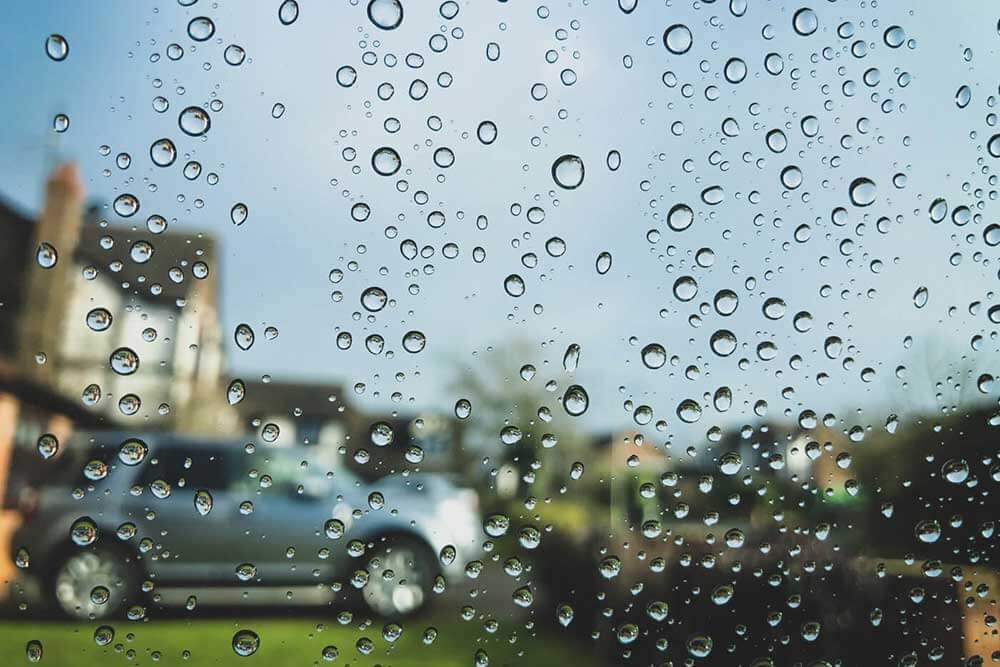 Rain drops on a window overlooking a neighbourhood