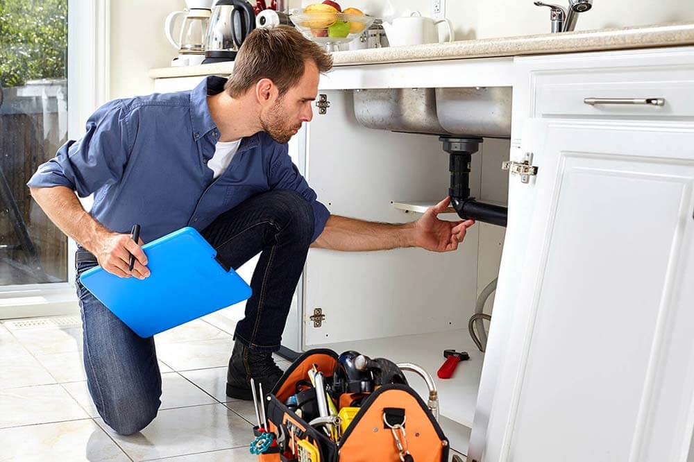 Homme inspectant la plomberie d'un domicile