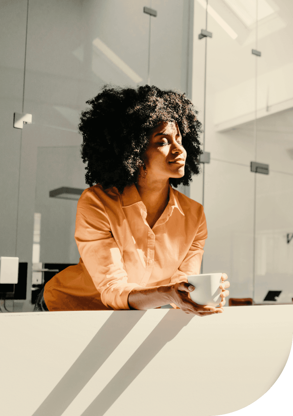 Une femme appuyée sur un rebord, tenant une tasse, avec le soleil qui rayonne sur elle.