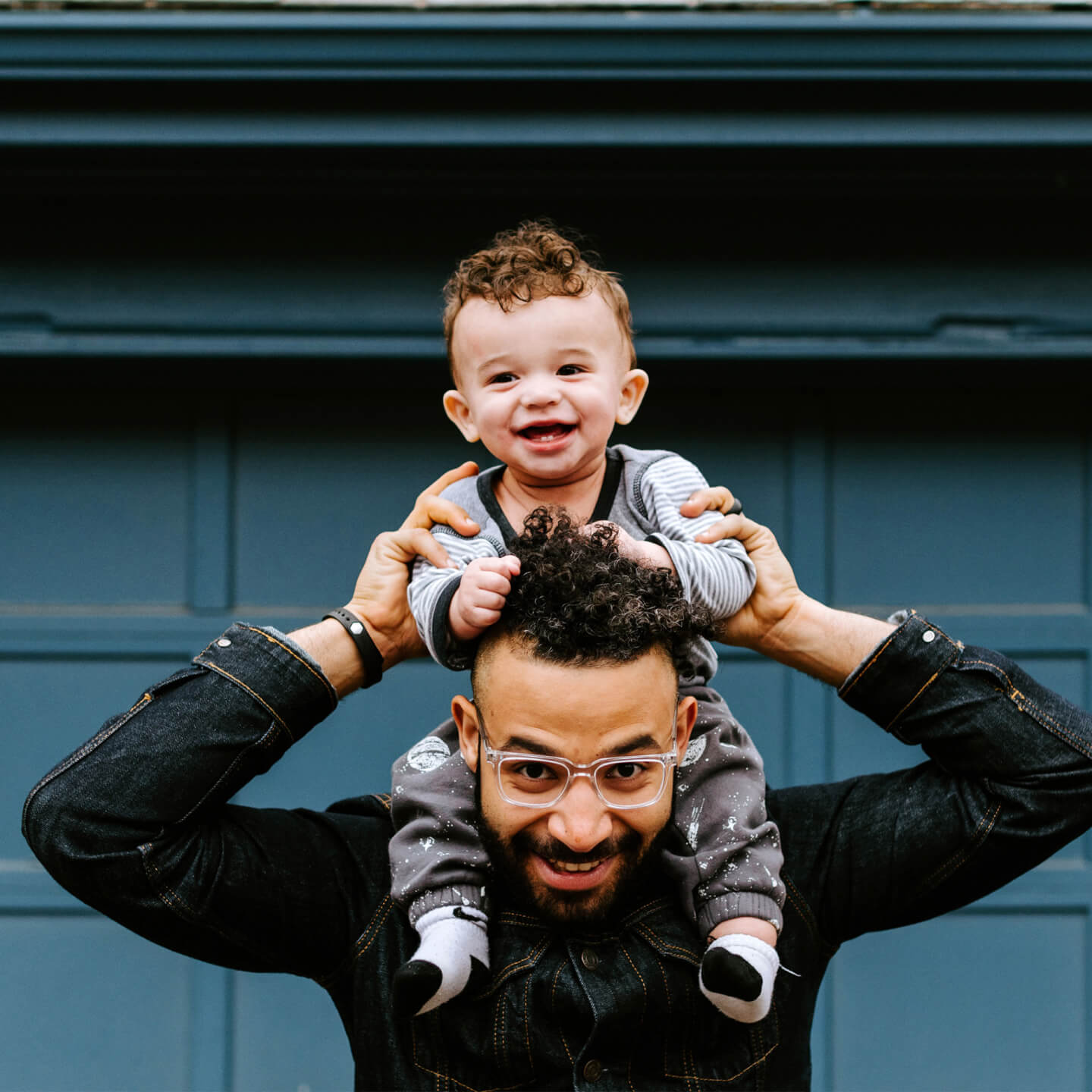 Un enfant assis sur les épaules de son père, souriant et profitant d’un moment amusant ensemble.