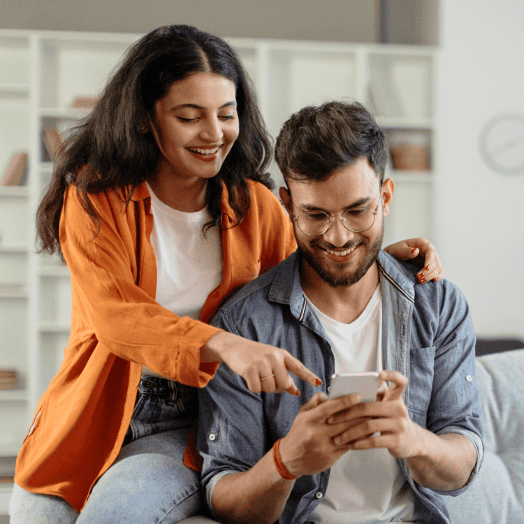 Un couple est heureux d’utiliser leur téléphone intelligent pour obtenir une soumission d’assurance habitation en ligne.