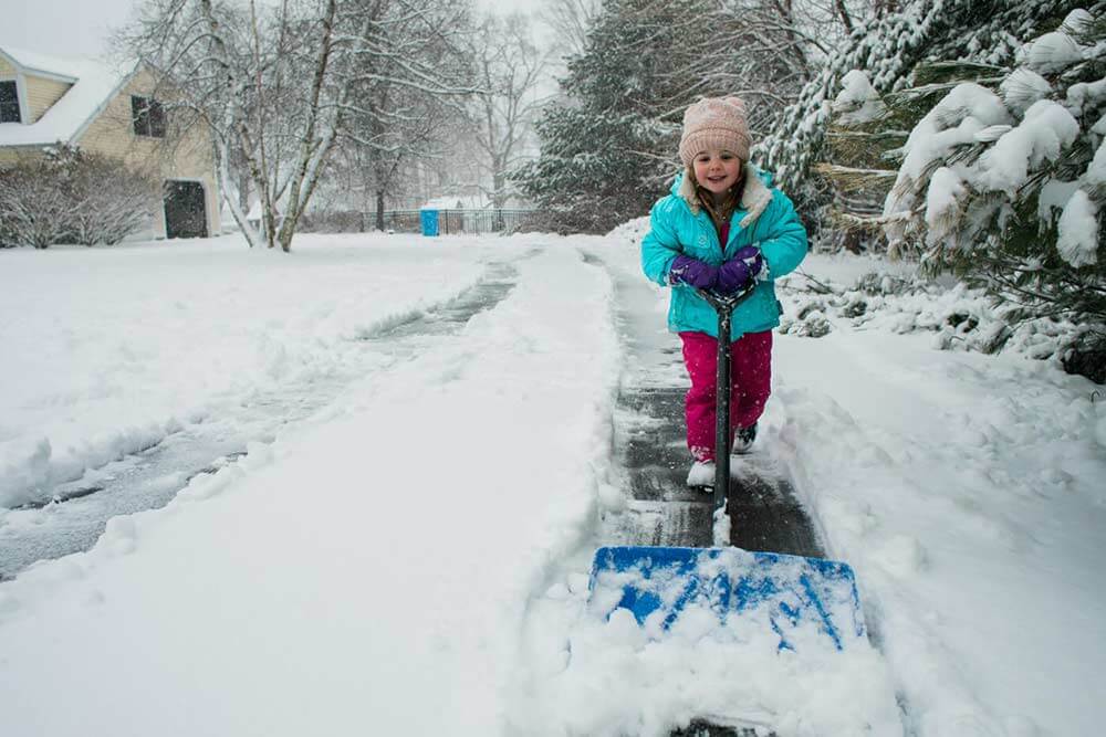 Child removing snow with a shovel