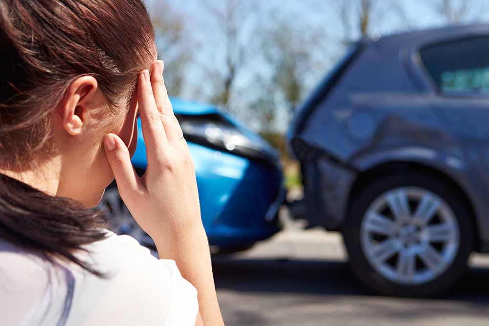 Woman sitting by a car collision