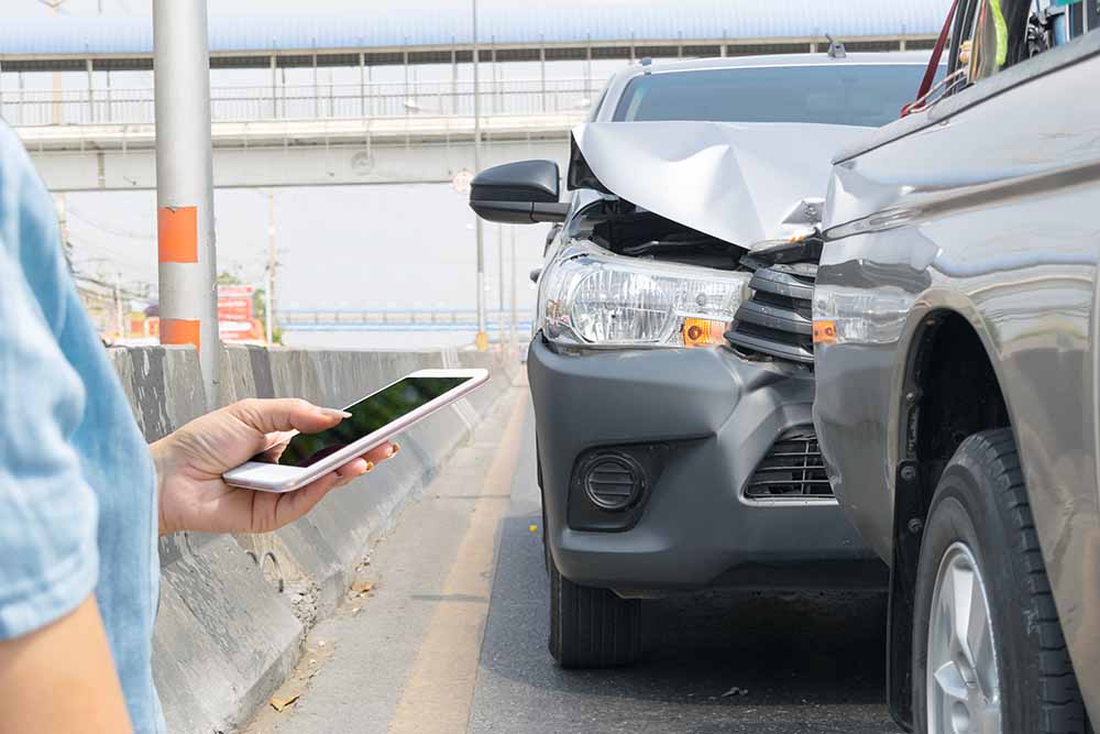 Une femme documente un accident de voiture avec son téléphone intelligent