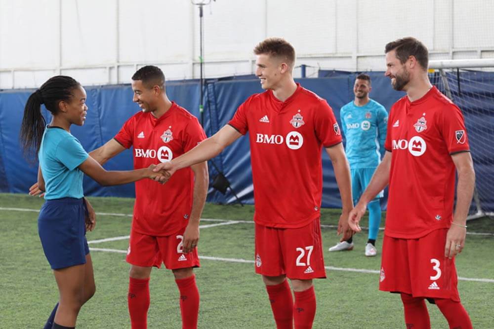 Joueurs de la TFC qui serrent la main à une jeune fille