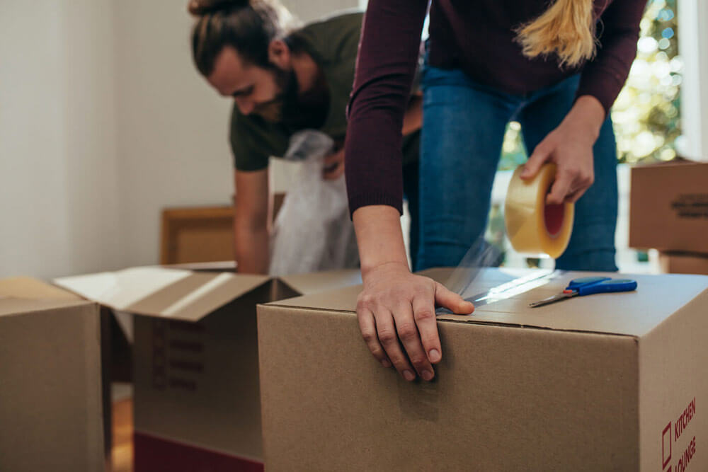 Man and woman taping up moving boxes