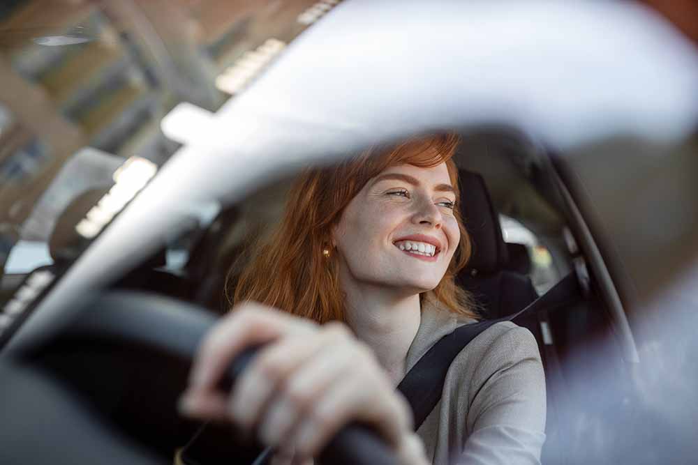 Femme souriante au volant d’une voiture