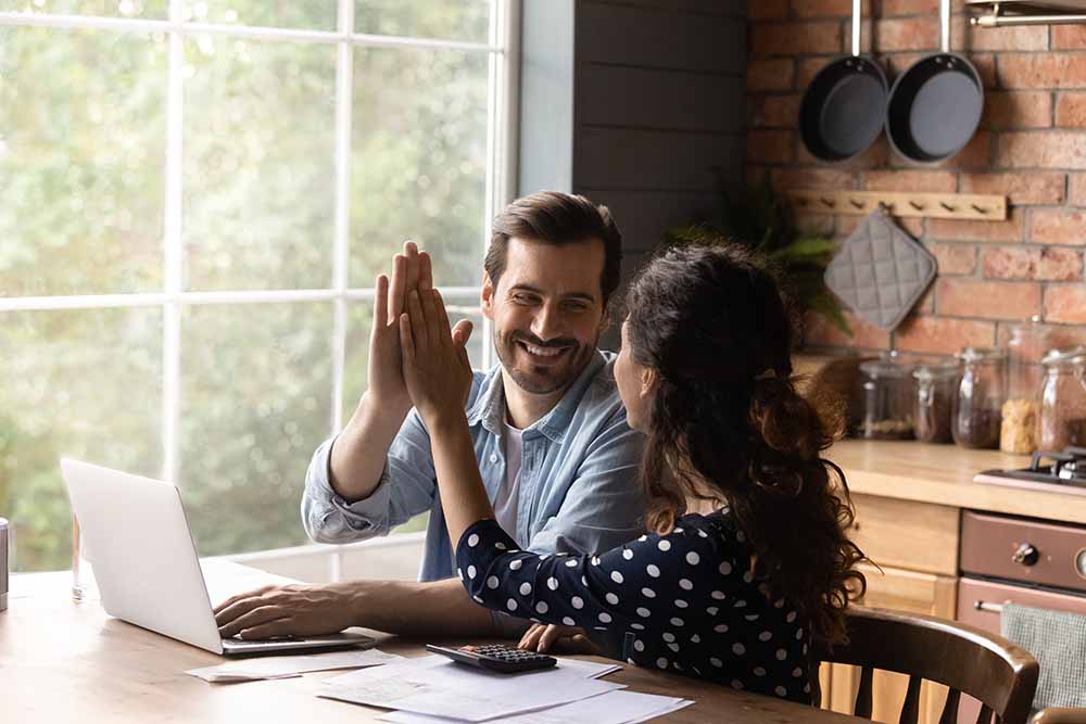 Young couple high-fiving as they do a financial review
