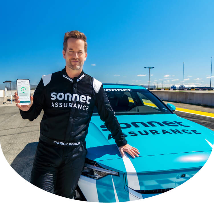 Patrick Benoit s’appuie contre une voiture sport, il tient un téléphone intelligent qui affiche sa note de conduite Sonnet Virage sur l’application de Sonnet Assurance.