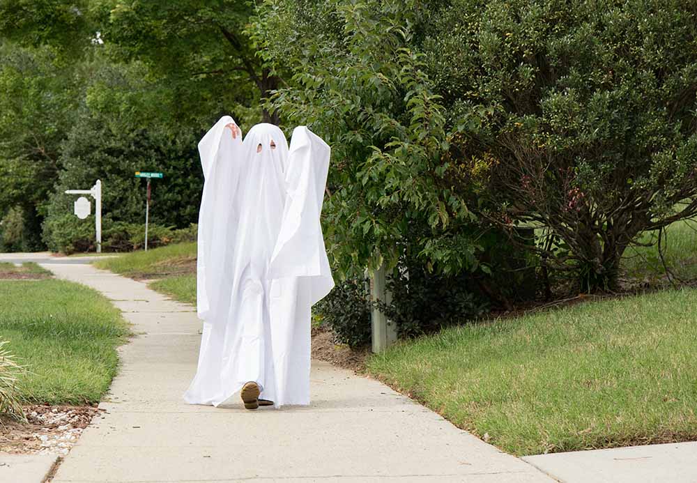 Un enfant dans un costume de fantôme fait à partir d’un drap