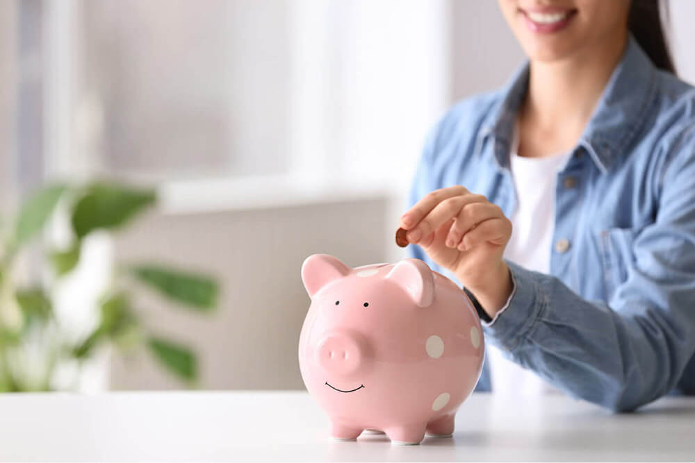 Woman depositing money into a piggy bank
