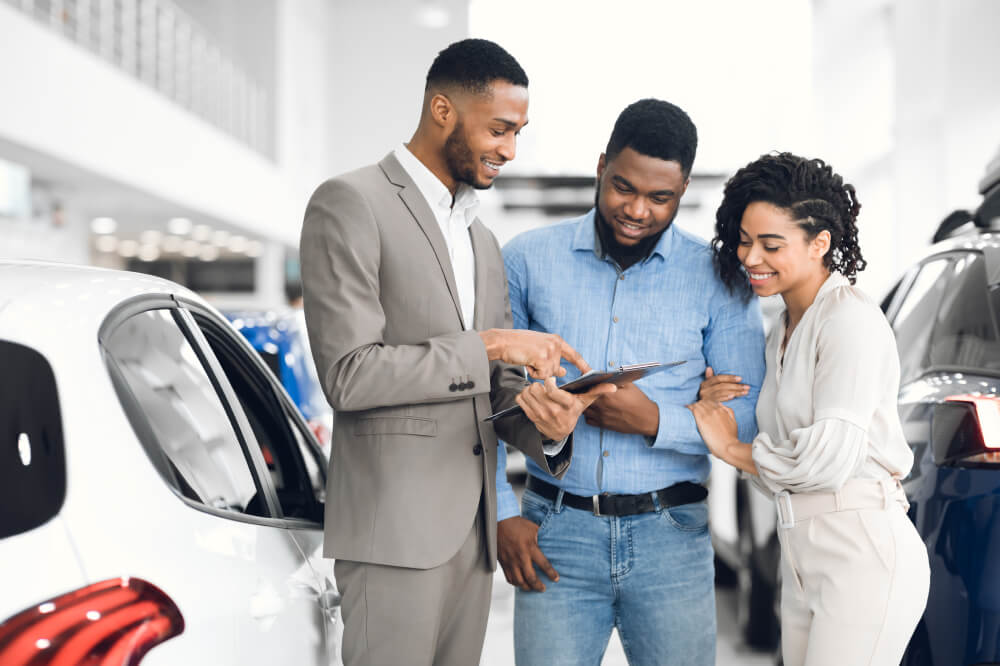 Couple at car dealership with car insurance