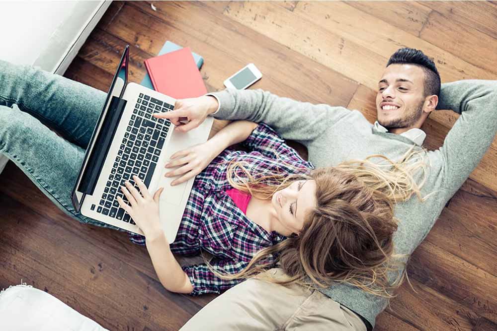 Homme et une femme sur le sol avec un portable ouvert