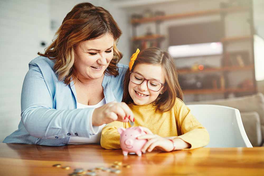 Mother and young daughter with a piggy bank