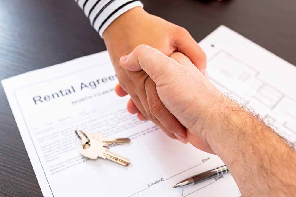 Two people shaking hands over a rental agreement