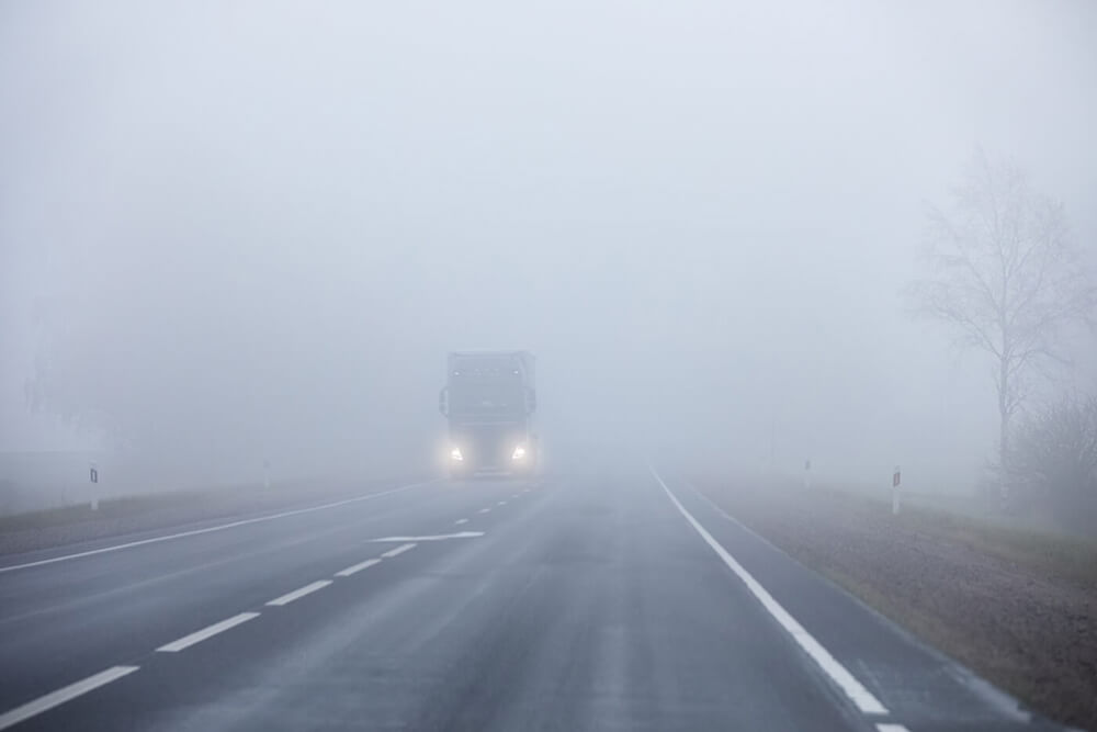 Route brumeuse avec un camion qui s’approche