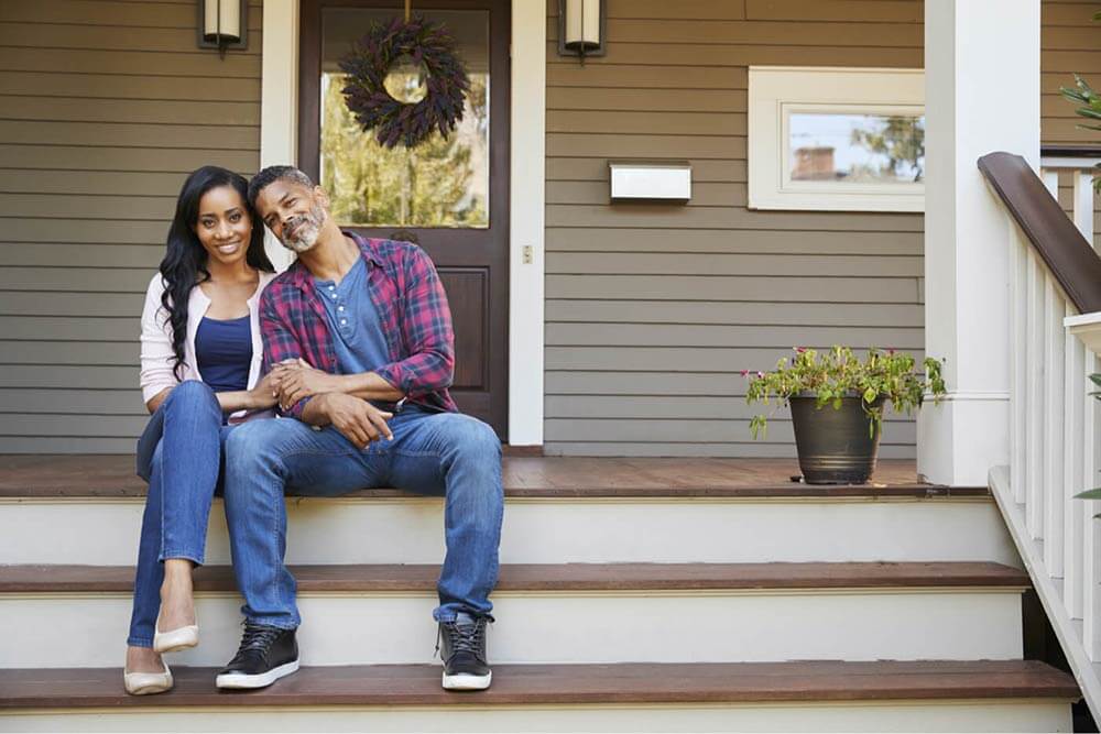 Couple sitting on fronts steps of their home