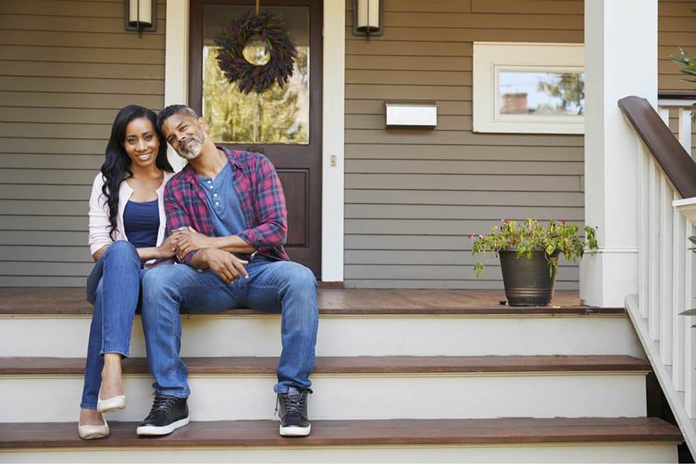 Couple assis sur l’escalier avant de leur maison