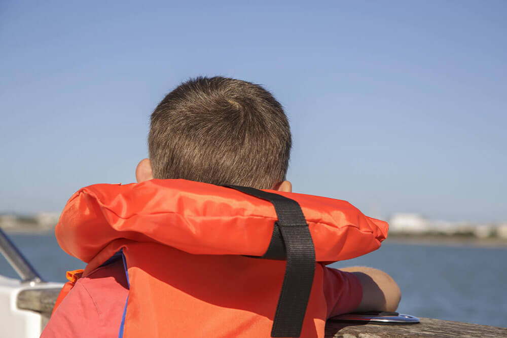 Kid in life jacket on a lake