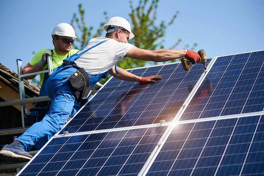 Workers installing a solar panel on a home