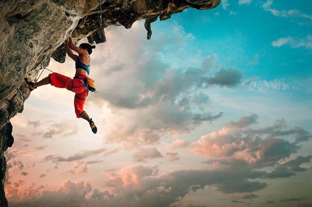 Active woman rock climbing at sunset