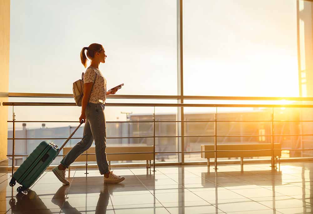Jeune femme marchant dans un aéroport avec sa valise