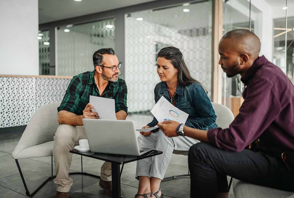 Three people looking at financial reports