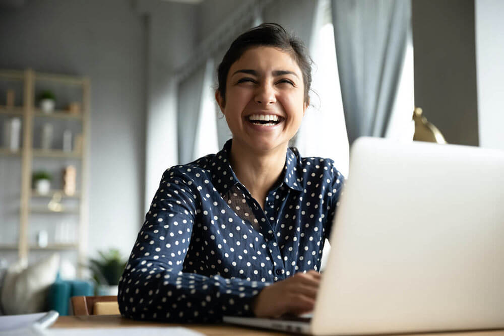 Cheery girl on computer buying insurance online