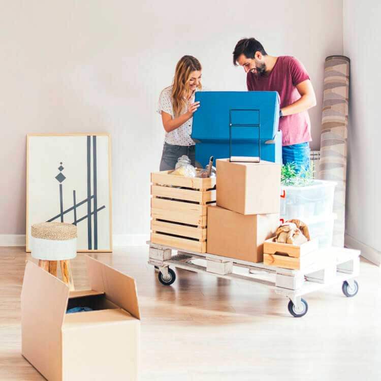 Un couple souriant déballe ses effets personnels dans son appartement assuré.