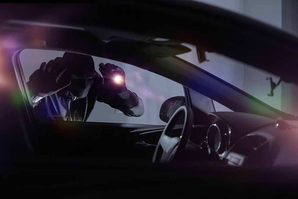 Un voleur de voiture tient une lampe de poche