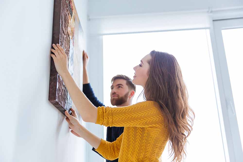 Un homme et une femme accrochant un tableau au mur