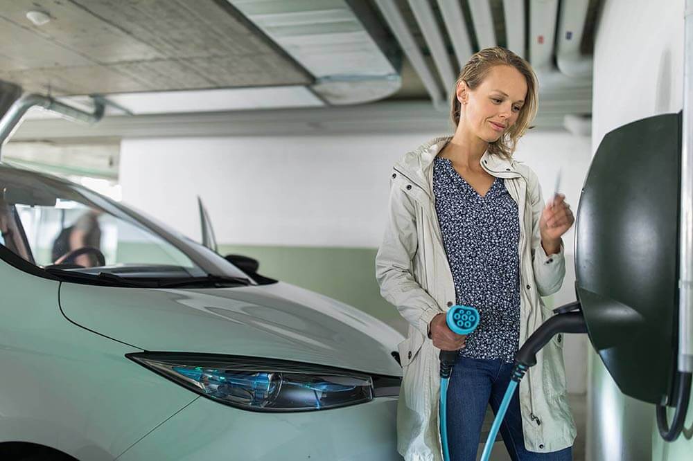 Femme en train de recharger un véhicule électrique