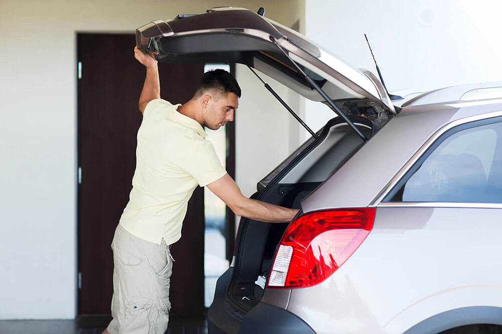 Young man opening his car trunk