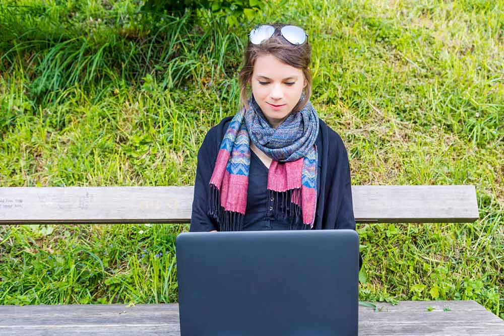 Millenial woman on laptop outside