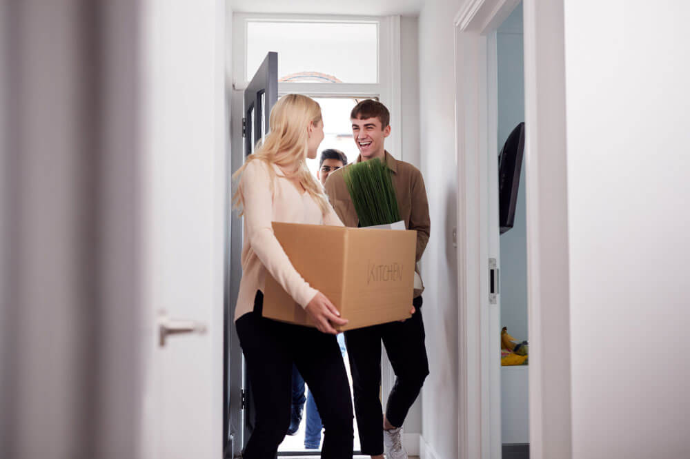 Groupe d'étudiants universitaires transportant des boîtes de déménagement dans leur nouvel appartement