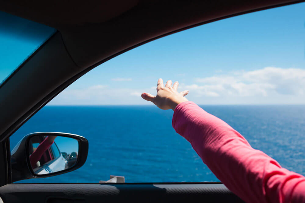 Femme avec la main sortie de la fenêtre de sa voiture