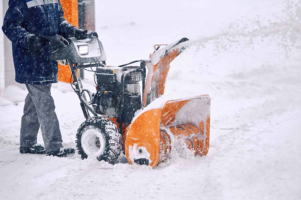 Personne utilisant une souffleuse à neige pour déneiger