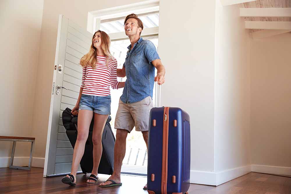 Un jeune couple traînant des valises arrive à une résidence de vacances