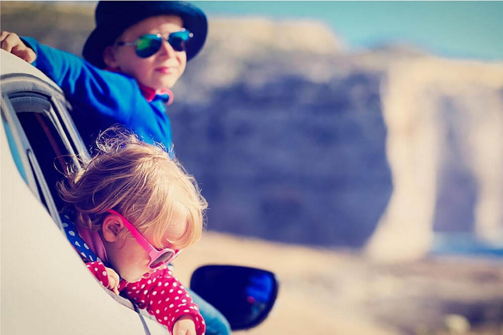 Two kids sticking their head outside of a car window