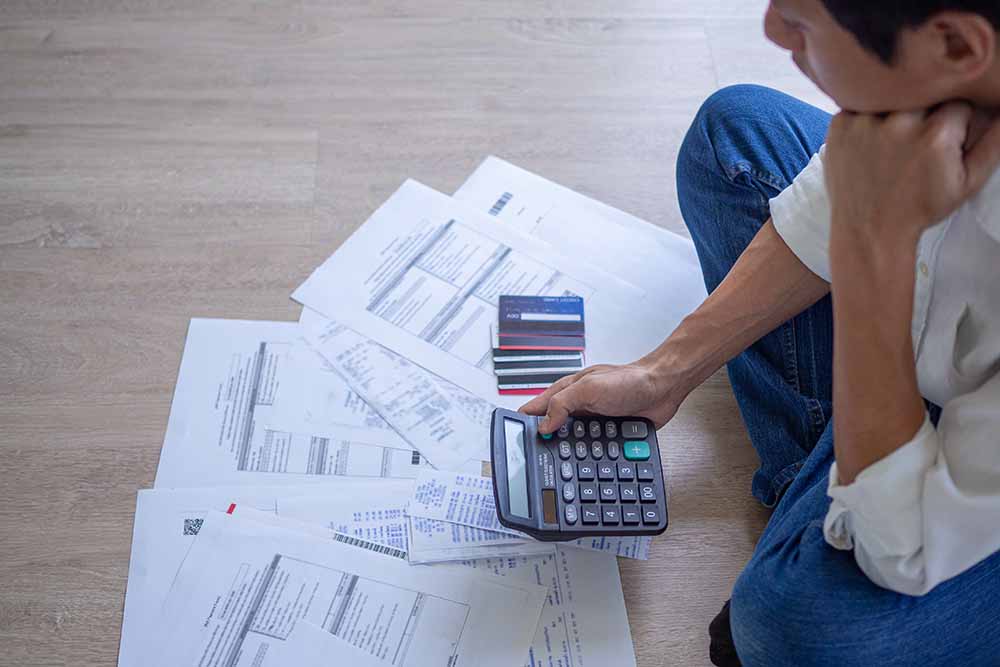 A man calculating credit card bills on the floor